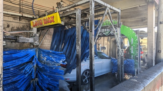 A white car going through the 32nd. St. Carwash just passing through the lava wax section.