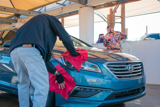 Soft Cloth employees hand drying a car after a wash.